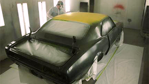 Empleado de taller pintando un coche con las medidas de seguridad reglamentarias
